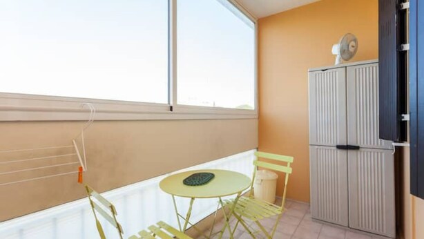 A balcony with a small table and chairs, a radiator, and a cabinet.