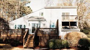 A two-story house with a front porch, a staircase leading to the second floor, and a fenced yard. - Newly renovated modern & spacious home complete with a private pool! (Apex)