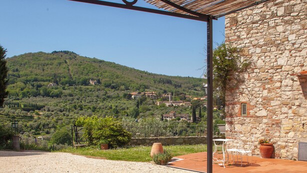 A table with a green tablecloth and a vase of pink flowers, set outdoors with a view of a stone building and a hillside in the background. - Charming studio with all amenities in stone house-Tuscany, 8 miles from Florence (Toscana)