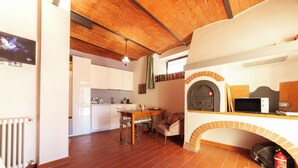 A kitchen with a brick oven, a dining area with a table and chairs, and a white cabinet. - Charming studio with all amenities in stone house-Tuscany, 8 miles from Florence (Toscana)