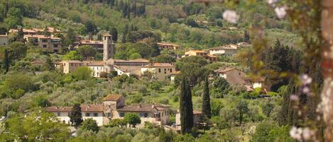 A hillside village with traditional architecture, stone walls, and a mix of residential and commercial buildings.