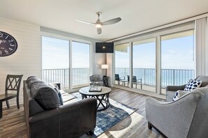 Ein geräumiger Balkon mit Meerblick, ausgestattet mit einer Couch, einem Sessel und einem runden Tisch.