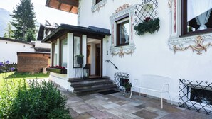 Ein weißes Gebäude mit verzierten Fensterrahmen, einer Holztür und einer kleinen Veranda mit Stufen.