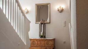 Eine Treppe mit weißer Geländer, ein Holzkasten mit Spiegel darüber und Wandleuchten.