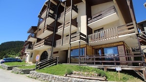 Un edificio de varios pisos con balcones, un cartel que dice 'Hotel Services' y un muro de piedra al frente.