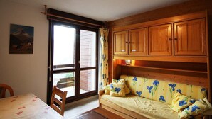 Una habitación con un banco de madera, una mesa y un amplio ventanal con cortinas.