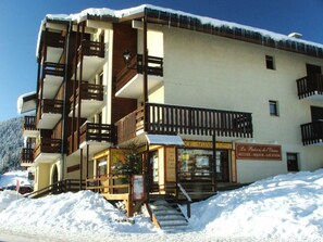 Un immeuble à plusieurs étages doté de balcons, une enseigne indiquant l’emplacement et un escalier menant à l’entrée.
