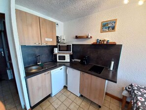 A compact kitchen with a microwave, coffee maker, and a small sink. - 150m from ski slopes, Ground floor, view mountain, terrace, parking, tv, ski locker, 23m² (Auris)