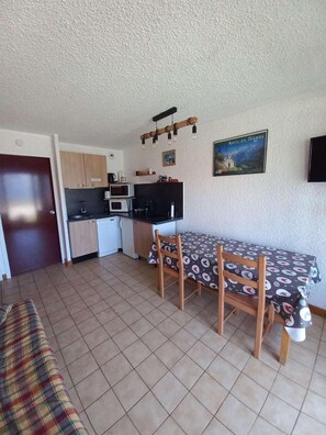 A compact living space with a kitchenette, a dining table with chairs, and a sofa. - 150m from ski slopes, Ground floor, view mountain, terrace, parking, tv, ski locker, 23m² (Auris)