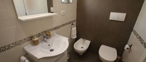 Une salle de bain équipée d’un lavabo, d’un bidet et de toilettes.