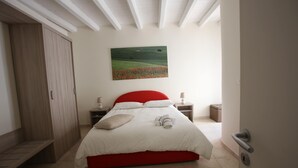 A bedroom with a bed, a nightstand, a lamp, a painting, and a wardrobe. - CASA RUBIS (Ruvo di Puglia)