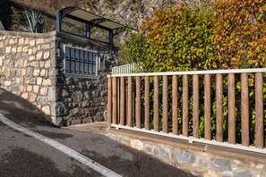 entrance with stone wall and metal gate, surrounded by lush greenery.