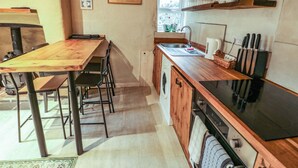 Una cocina compacta con una mesa de madera, sillas, lavadora y estufa.
