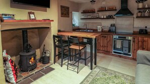 Una cocina acogedora con chimenea, vigas de madera, un televisor y una cafetera.