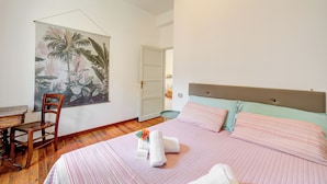 A bedroom with a bed, a chair, a desk, and a large floral painting on the wall. - Casa Rachele Stresa Center (Stresa)