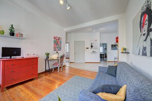 Uma sala de estar moderna com um aparador vermelho, um sofá cinza e uma televisão sobre um móvel.