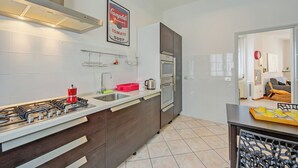 A modern kitchen with a gas stove, stainless steel appliances, and a tiled backsplash. - Casa Rachele Stresa Center (Stresa)