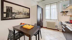 A dining area with a table set for two, a fruit bowl, and a framed cityscape picture on the wall. - Casa Rachele Stresa Center (Stresa)