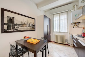 A dining area with a table, chairs, a fruit tray, and a framed cityscape picture. - Casa Rachele Stresa Center (Stresa)