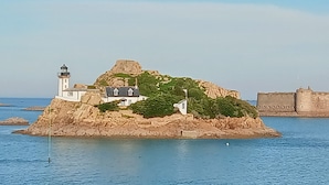 Une île côtière dotée d’un phare, d’une petite maison et d’une fortification.