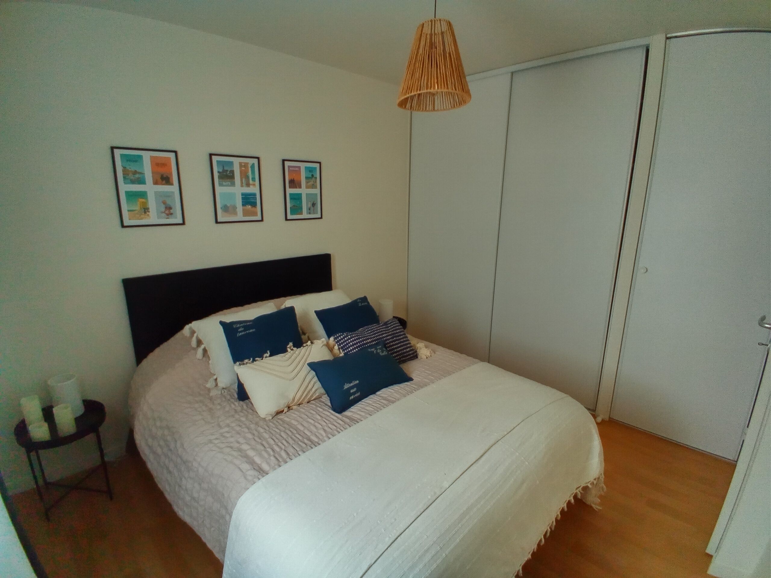 A bedroom with a bed, a bedside table with candles, and a wardrobe.