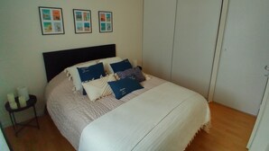 Une chambre à coucher avec un lit, une table de chevet avec des bougies et une armoire.