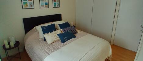 A bedroom with a bed, a bedside table with candles, and a wardrobe.
