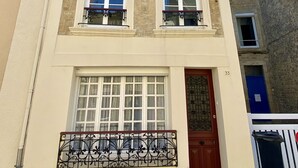 Un edificio de varios pisos con fachada color crema, ventanas con marcos blancos y barandillas de hierro decorativas en los balcones.