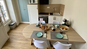 Una cocina compacta con electrodomésticos modernos, un comedor con dos sillas blancas y vistas al exterior.