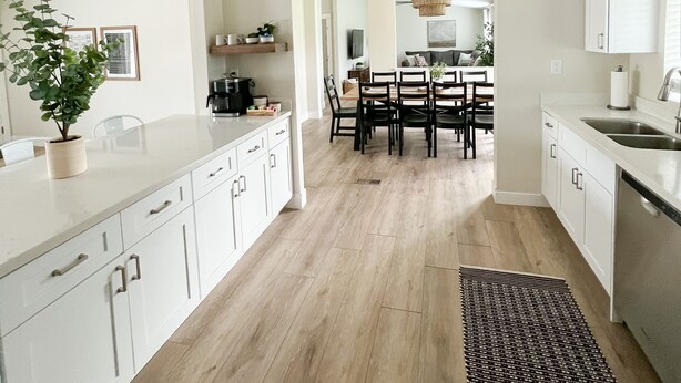 Cozinha moderna com armários brancos, uma ilha central e um espaço de refeições com lustre.