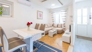 A modern living room with a dining table, sofa, and a TV stand. - Apartments Lucija - Two Bedroom Apartment With Balcony and Sea View (Dubrovnik)