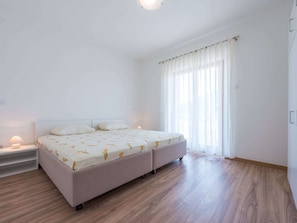 Ein Schlafzimmer mit einem Bett, Nachttischen und einem Fenster mit Vorhängen.