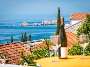 A coastal view with a table set for dining, overlooking the sea and rocky outcrops. - Apartments Lucija - Two Bedroom Apartment With Balcony and Sea View (Dubrovnik)