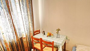 A dining area with a table set for two, featuring a patterned tablecloth, wooden chairs, and a vase with flowers. - Apartments Lemes - One Bedroom Apartment With Garden View Apt4 (Janjina)
