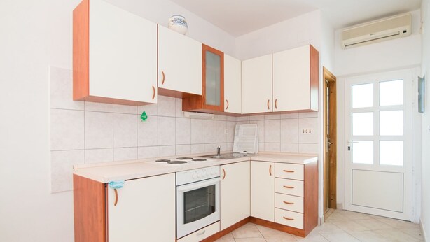 A kitchen with white cabinets, a stove, and a sink. - Apartments Neva- One Bedroom Apartment (Selca)