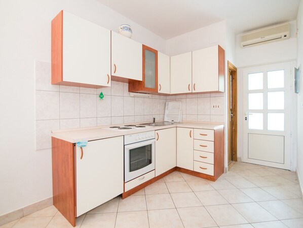 Une cuisine avec des meubles blancs, une cuisinière et un évier.