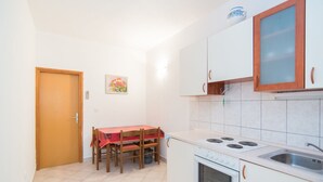 A compact kitchen with a dining table, a stove, and cabinets. - Apartments Neva- One Bedroom Apartment (Selca)