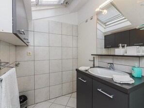 A modern bathroom with a skylight, a large mirror, and a vanity with a sink and towel rack. - Apartments Roda - Comfort One Bedroom Apartment With Terrace - (Supetar)
