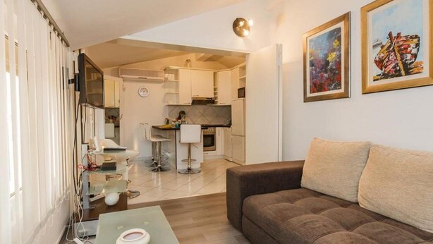 A modern living room with a sofa, a coffee table, and a kitchen in the background. - Apartments Roda - Comfort One Bedroom Apartment With Terrace - (Supetar)
