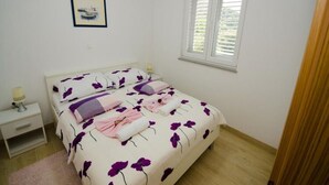 Ein Schlafzimmer mit Bett, Nachttisch, Fenster mit Jalousien und einem gerahmten Bild an der Wand.
