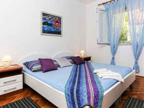 Una cama bien hecha con un edredón a rayas, dos almohadas y una lámpara de noche.