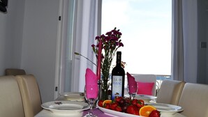 A dining table set with plates, cutlery, a bottle of wine, a glass, and a fruit platter. - Apartments Lina - Three Bedroom Apartment With Two Balconies and Sea View (Dubrovnik)