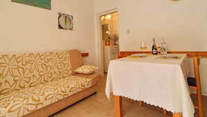 A cozy living room with a sofa and a dining table set for two. - Apartments Villa Marijana - One Bedroom Apartment With Terrace and Garden View (Blato)
