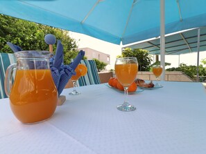 A table set outdoors with a pitcher of orange juice, two wine glasses, and a plate with pastries. - Apartments Villa Marijana - One Bedroom Apartment With Terrace and Garden View (Blato)