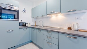 Une cuisine moderne avec des meubles de couleur bleu clair, des appareils en acier inoxydable et un four encastré.