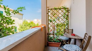 Un petit balcon avec une table et des chaises en bois, un treillage et des plantes en pot.