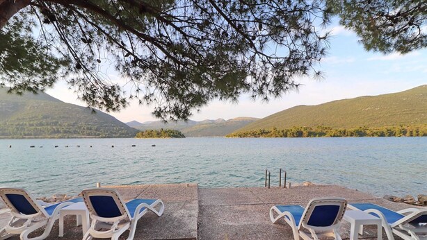 A lakeside view with lounge chairs and a dock extending into the water. - Apartments More & Ja - One Bedroom Apartment With Terrace and Sea View (Ston)