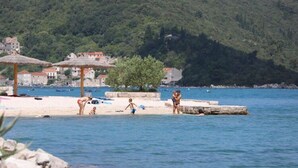 A coastal scene with a beach, umbrellas, and a few people. - Apartments More & Ja - One Bedroom Apartment With Terrace and Sea View (Ston)