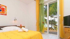 A hotel room with a bed, a television, and a view of the outdoors. - Apartments More & Ja - One Bedroom Apartment With Terrace and Sea View (Ston)