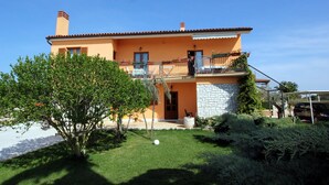 A two-story house with a balcony, a stone facade, and a well-maintained garden. - Apartment in Fazana With Garden & Terrace (Fazana)